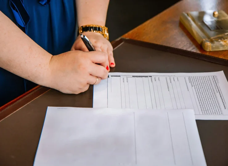 mujer firmando contrato en el escritorio de su abogado